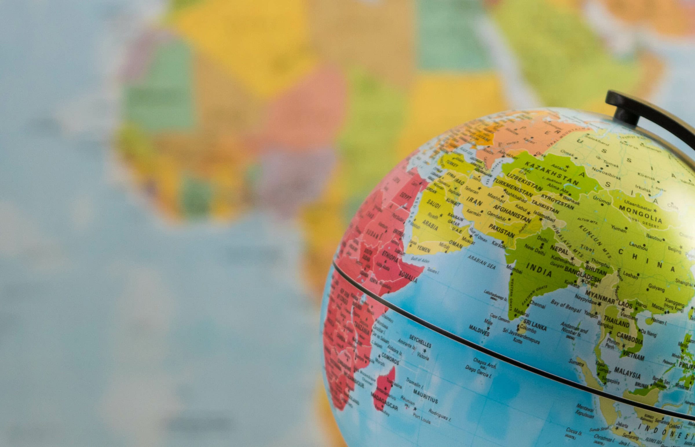 A globe focused on India with a blurred world map background