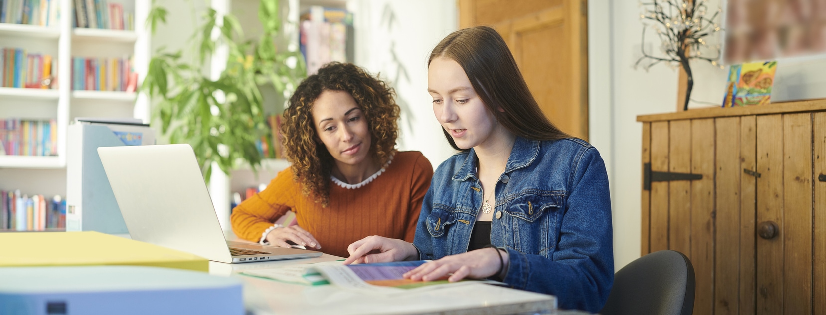 Two young women sitting at a desk, engrossed in their work on a laptop.