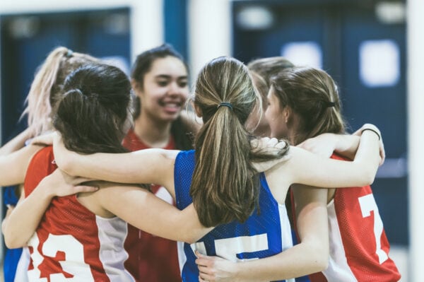 Female basketball players huddle in a circle.