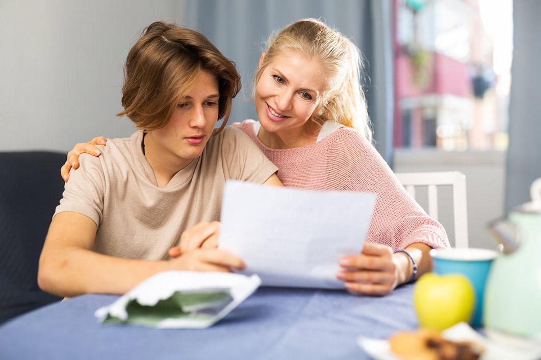 Interested teenager reading with happy mother