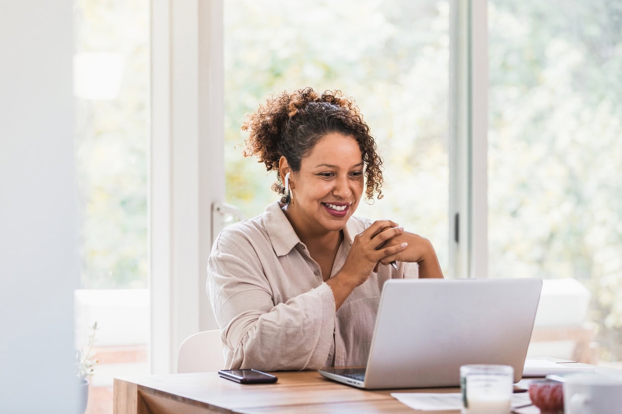 Using laptop and bluetooth earbuds, woman video conferences from home