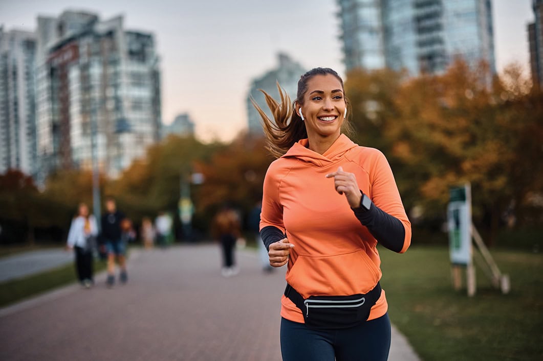 Happy woman listening to music on earphones while jogging.
