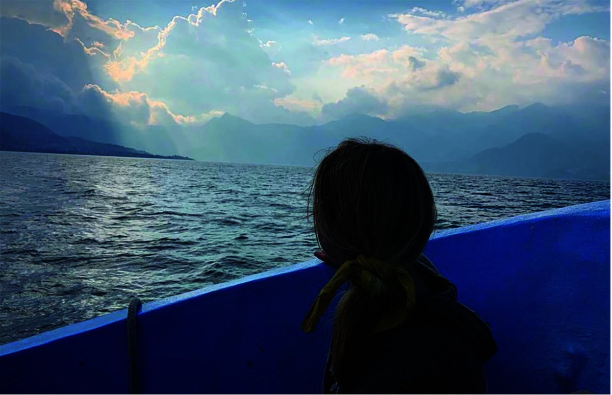 A young woman looks out at the water from a boat