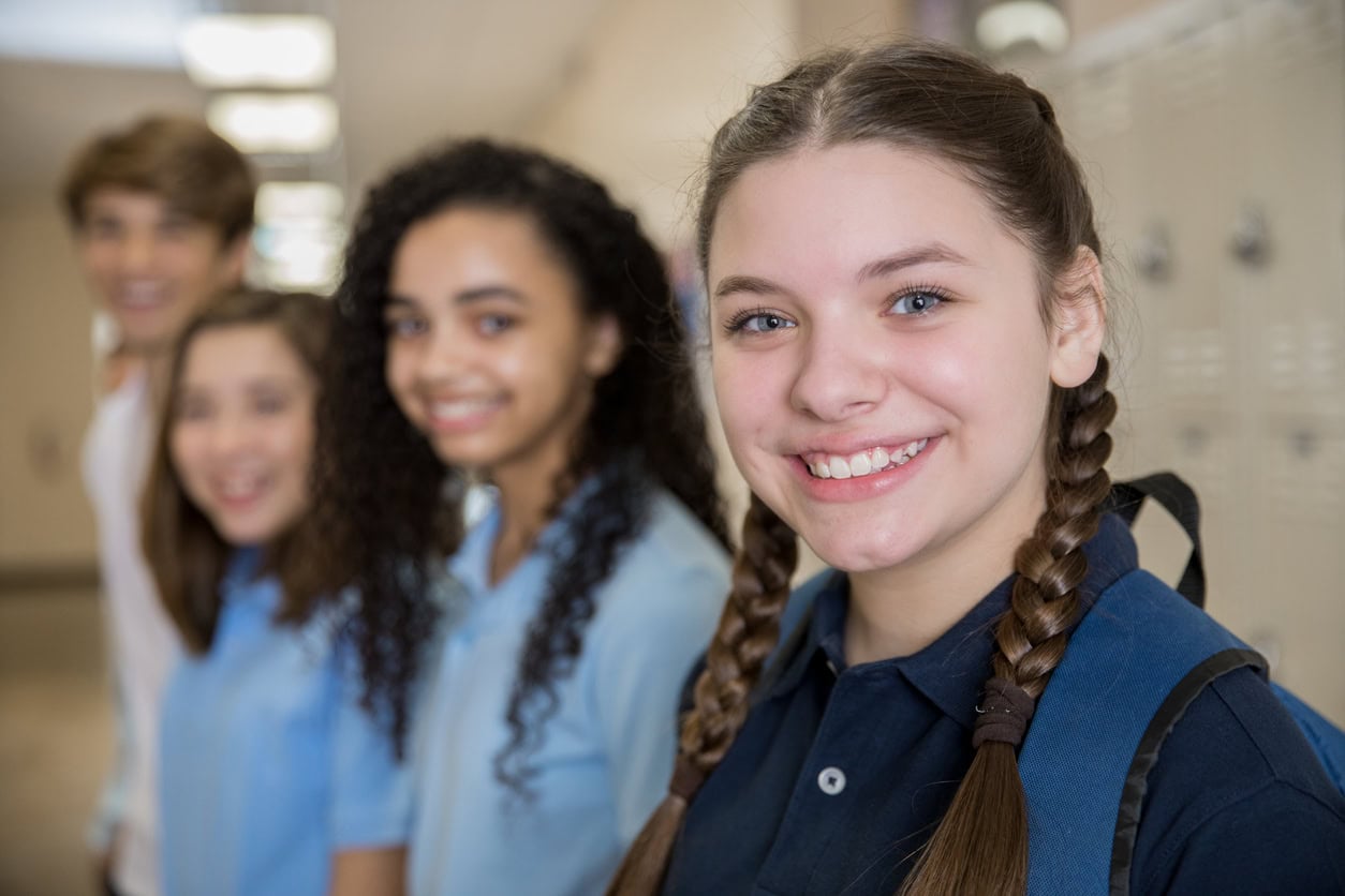 Happy high school students smiling by lockers