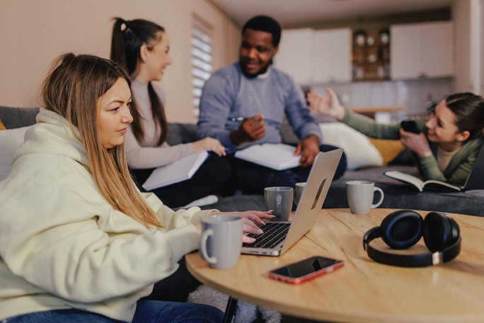 Group of four multiracial young people using common room