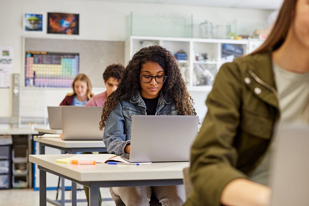 Students working on laptops in a classroom with copy space.
