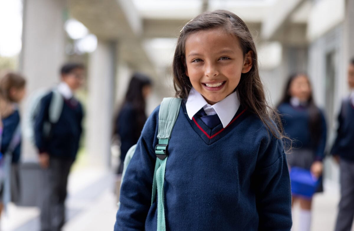 Portrait of a happy girl smiling in the corridor at the school and looking at the camera