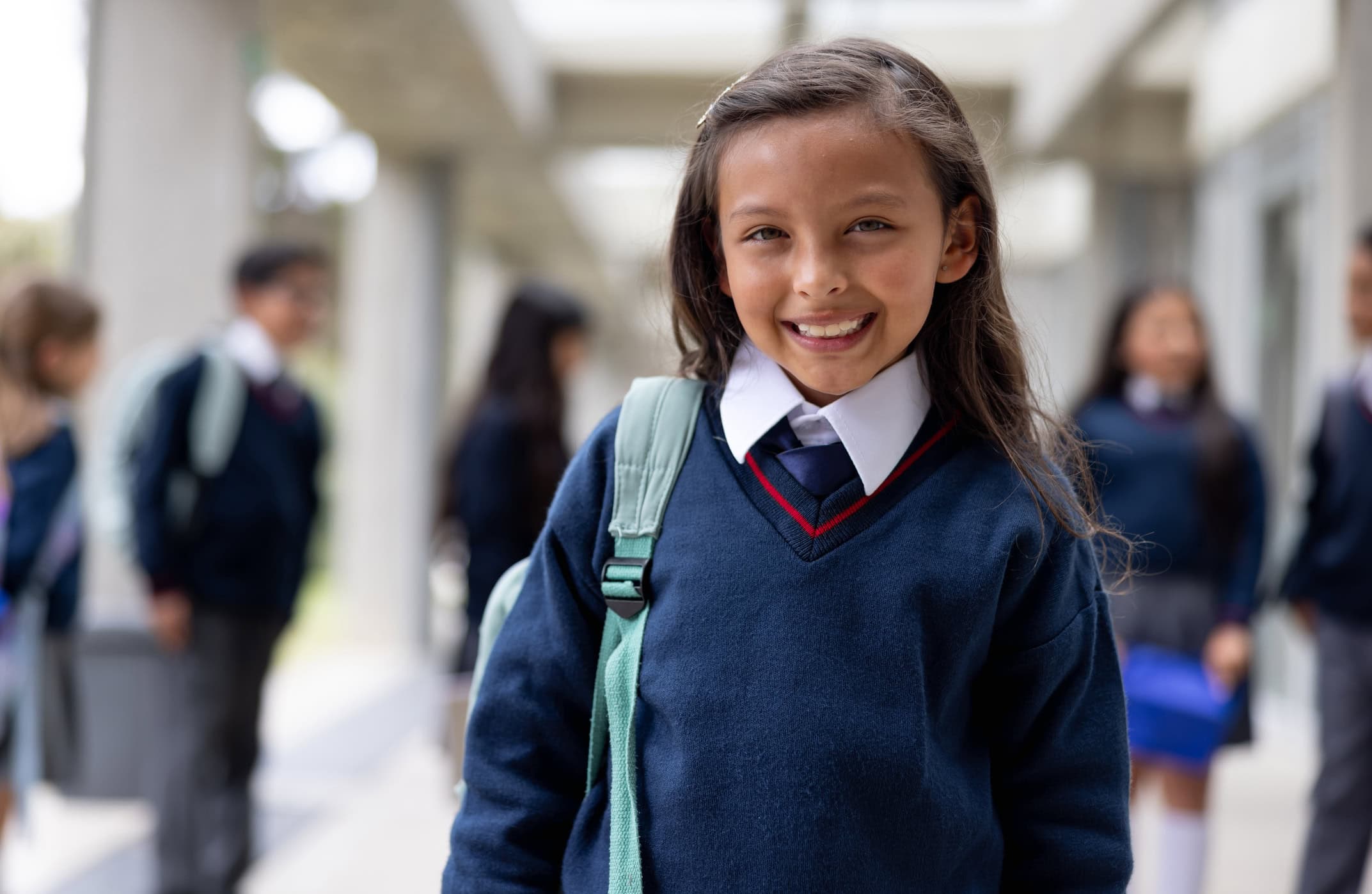 Portrait of a happy girl smiling in the corridor at the school and looking at the camera