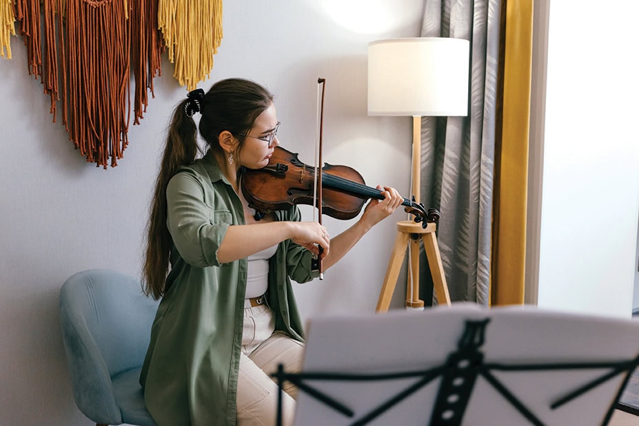 Focused young artist playing violin and studying music composition A dedicated violin student practices classical compositions, focusing on precision and technique