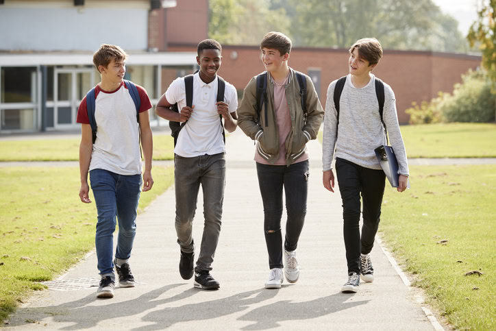 Group Of Male Teenage Students Walking Around School Campus